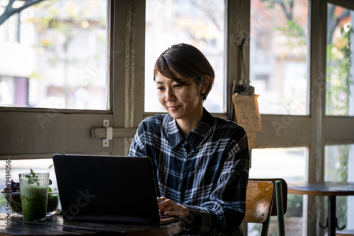 カフェでノートパソコンを見るミドル世代の日本人女性 photo