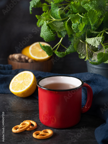 Red  cup of tea with lemon, mint and salt kracker on dark background. The concept of mood breakfast © Kufotos