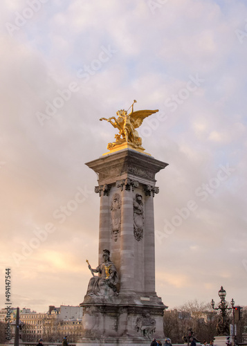 Column with a gilded pheme sculpture of Pont Alexandre III at sunset in Paris, France