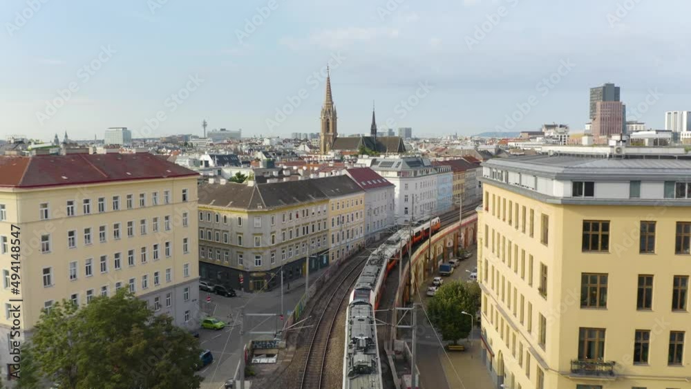 Vienna U-Bahn Train Travels Above City Street between Colorful Buildings on Beautiful Summer Day in Austria's Capital City Vienna U-Bahn Train Travels Above City Street between Colorful Buildings on Beautiful Summer Day in Austria's Capital City