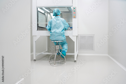 Unidentified microbiologist is testing the sample under the laminar air flow cabinet in the clean room of quality control laboratory in pharmaceutical industry.