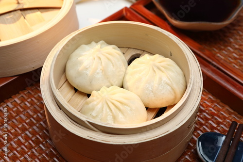 Delicious baozi, Chinese steamed meat bun is ready to eat on serving plate and steamer, close up, copy space product design concept.