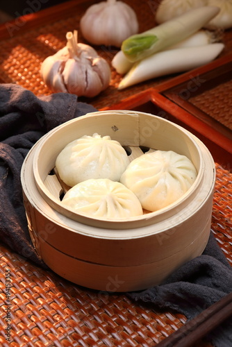 Delicious baozi, Chinese steamed meat bun is ready to eat on serving plate and steamer, close up, copy space product design concept.