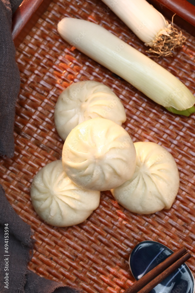 Delicious baozi, Chinese steamed meat bun is ready to eat on serving plate and steamer, close up, copy space product design concept.