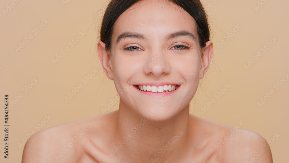 Young brunette beauty model with pure skin looks at camera and smiles widely | Skin care products promotional footage