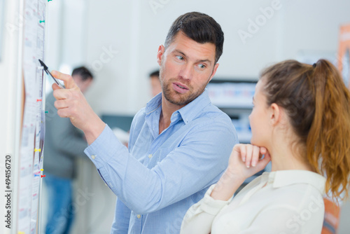 people talking and pointing something on a white board