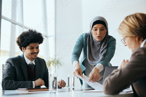 Middle Eastern businesswoman analyses reports with her coworkers during meeting in the office. photo