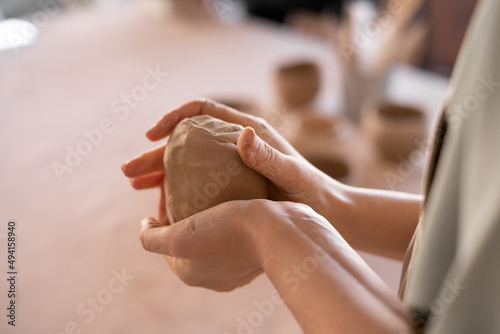 close-up of female potter's hand. professional ceramist at work using handmade cup making tools in studio, selective focus. the formation of handmade dishes. Art and small business concept