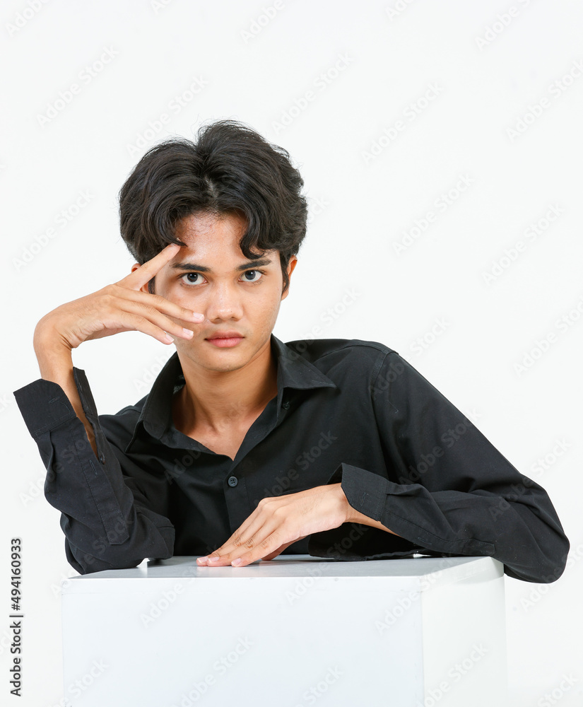 Portrait isolated cutout closeup studio shot of Asian young LGBTQ gay glamour handsome male model in casual black shirt sitting posing gesturing with square box look at camera on white background Portrait isolated cutout closeup studio shot of Asian young LGBTQ gay glamour handsome male model in casual black shirt sitting posing gesturing with square box look at camera on white background