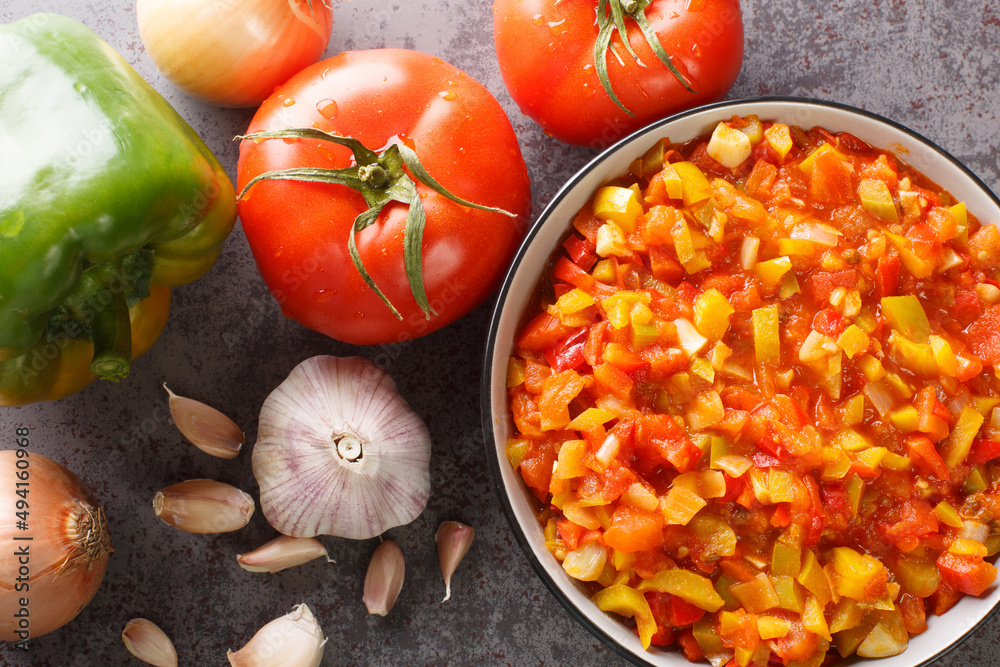Homemade sofrito sauce from peppers, tomatoes, garlic and onions close-up in a plate on the table. horizontal top view from above Homemade sofrito sauce from peppers, tomatoes, garlic and onions close-up in a plate on the table. horizontal top view from above