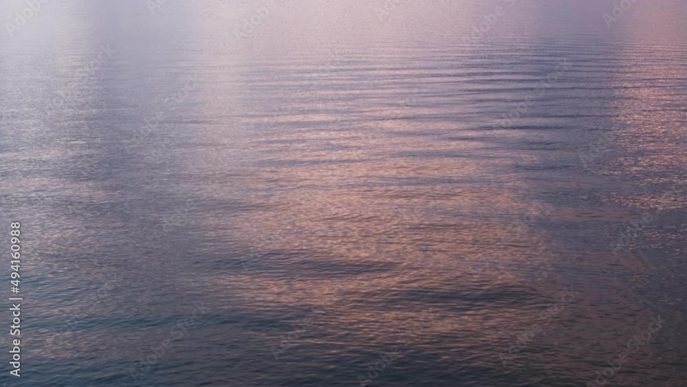 Moving lake water with pink sky reflections in the early morning Moving lake water with pink sky reflections in the early morning