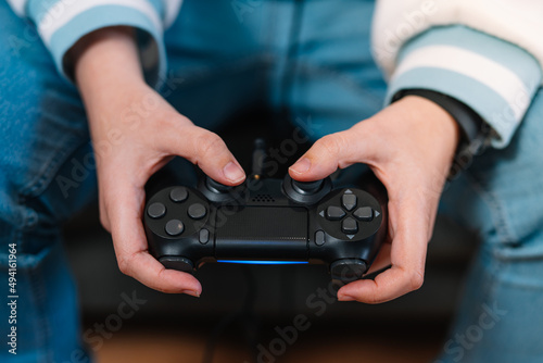 Detail shot of a young woman's hands with a video console controller playing a game.