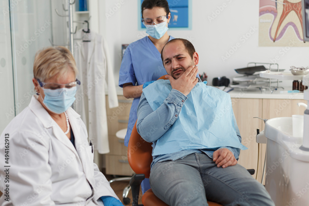 Obraz premium Specialist dentist team explaining caries infection to sick patient with toothache discussing medical expertise during stomatological consultation in dental office. Concept of medicine service