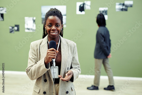 Horizontal medium portrait of young African American art gallery curator holding microphone speaking about current exhibition photo