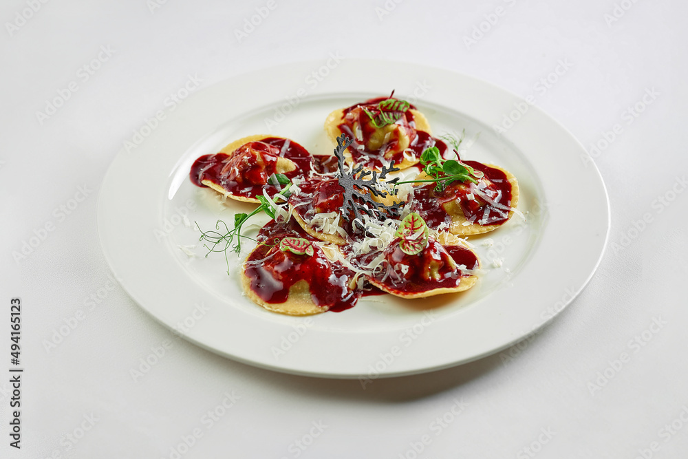 Ravioli with sauce and beef cheeks, Parmesan in a white plate on a white tablecloth Ravioli with sauce and beef cheeks, Parmesan in a white plate on a white tablecloth