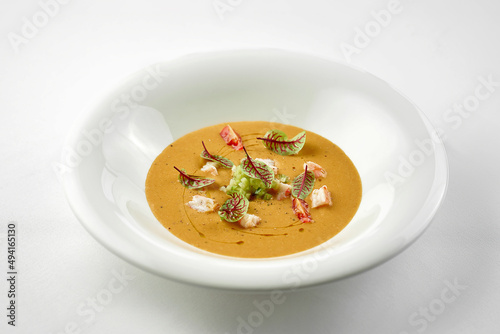 Close-up on pumpkin cream soup with crab in a white plate.
