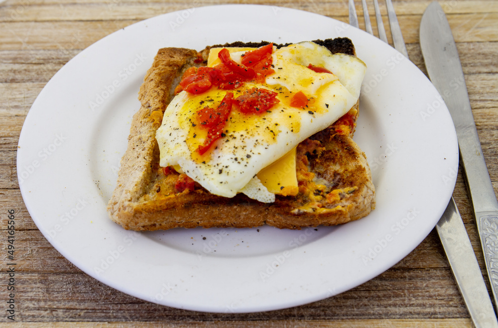 A fried egg on toast isolated on a small white side plate A fried egg on toast isolated on a small white side plate