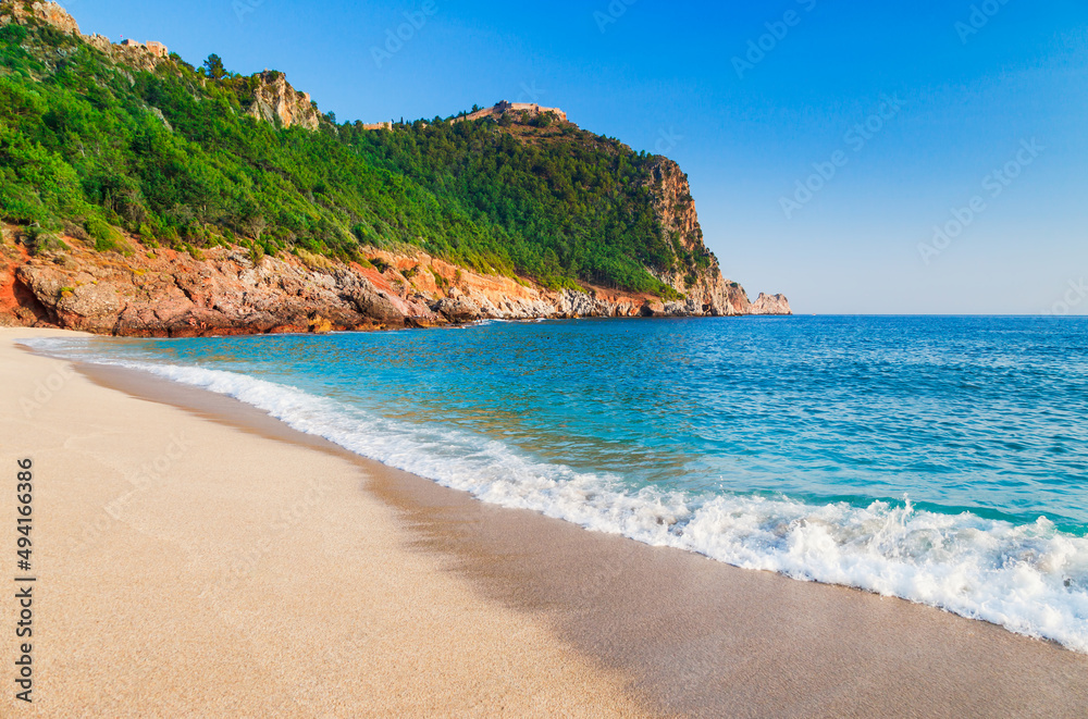 Cleopatra beach with beautiful sand and green rocks in Alanya peninsula, Antalya district, Turkey, Asia. Famous tourist destination with high cliff and ancient old Castle. Summer bright day