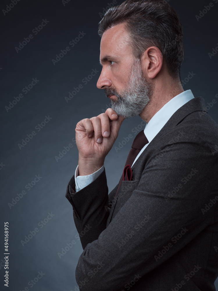 Portrait of a stylish elegant senior businessman with a beard and casual business clothes in photo studio isolated on dark background gesturing with hands Portrait of a stylish elegant senior businessman with a beard and casual business clothes in photo studio isolated on dark background gesturing with hands