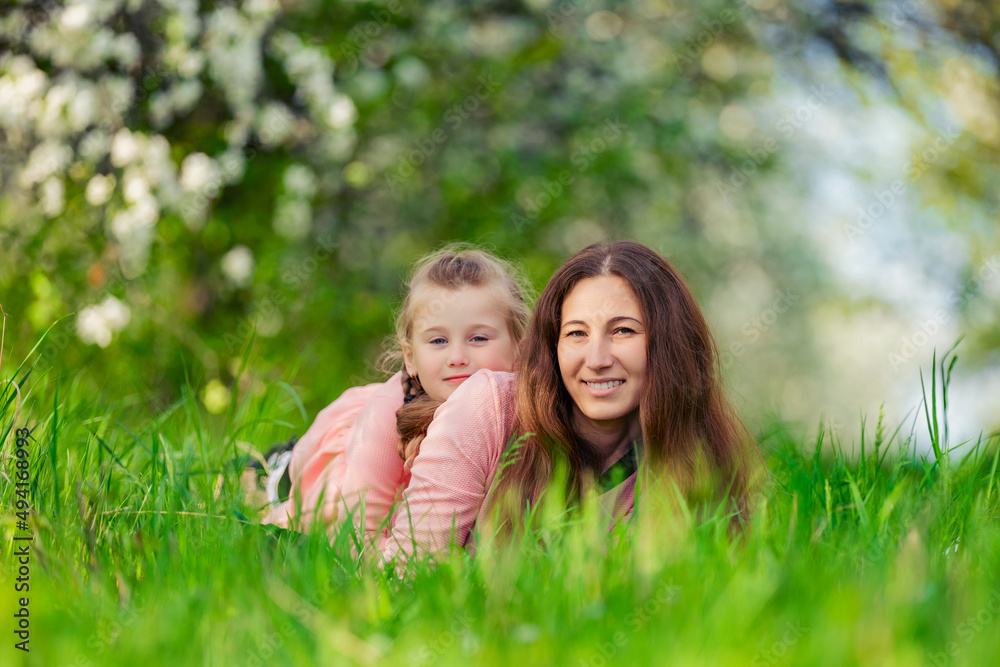 mother and daughter in identical dresses lie in the grass mother and daughter in identical dresses lie in the grass