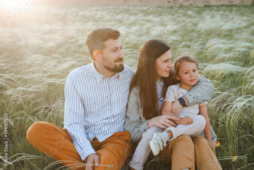 A hipster family walks in a summer field.
