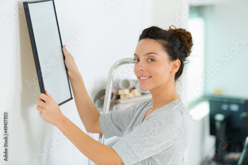 woman hanging picture on wall