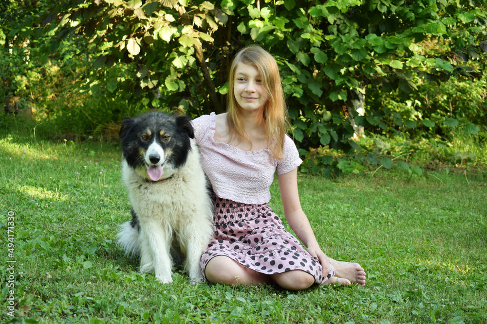 Girl playing with dog on grass. Teenager hugging Carpathian Shepherd Dog in the summer park. A Friendship concept of man and animal Girl playing with dog on grass. Teenager hugging Carpathian Shepherd Dog in the summer park. A Friendship concept of man and animal