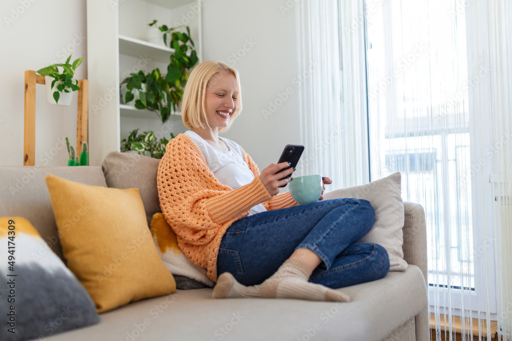 Young woman sit relax on sofa in living room browsing surfing wireless internet on smartphone, millennial girl rest on couch at home message text on modern cellphone, shopping online via website Young woman sit relax on sofa in living room browsing surfing wireless internet on smartphone, millennial girl rest on couch at home message text on modern cellphone, shopping online via website