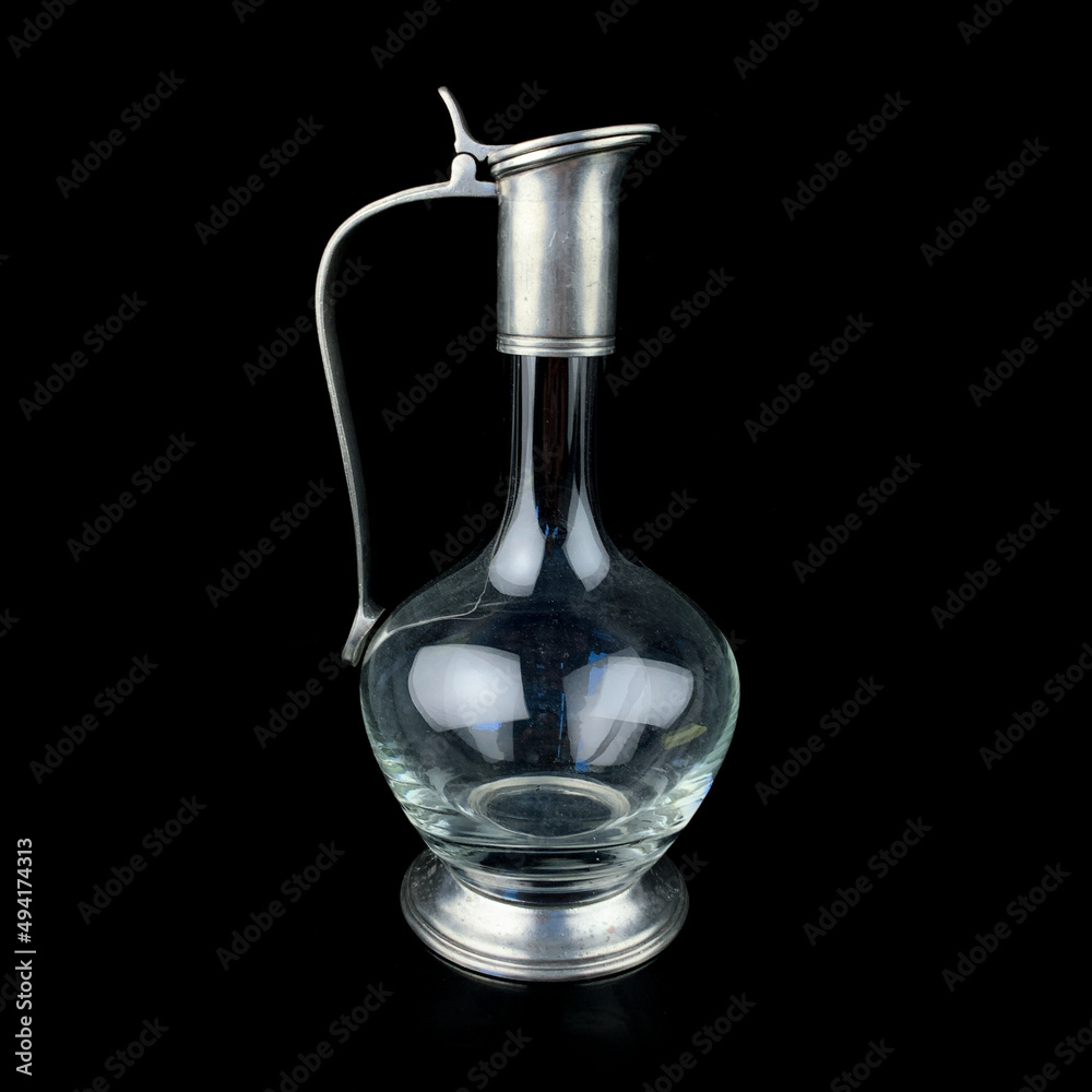antique glass decanter with a metal figured neck. retro decanter for alcohol on a black isolated background antique glass decanter with a metal figured neck. retro decanter for alcohol on a black isolated background