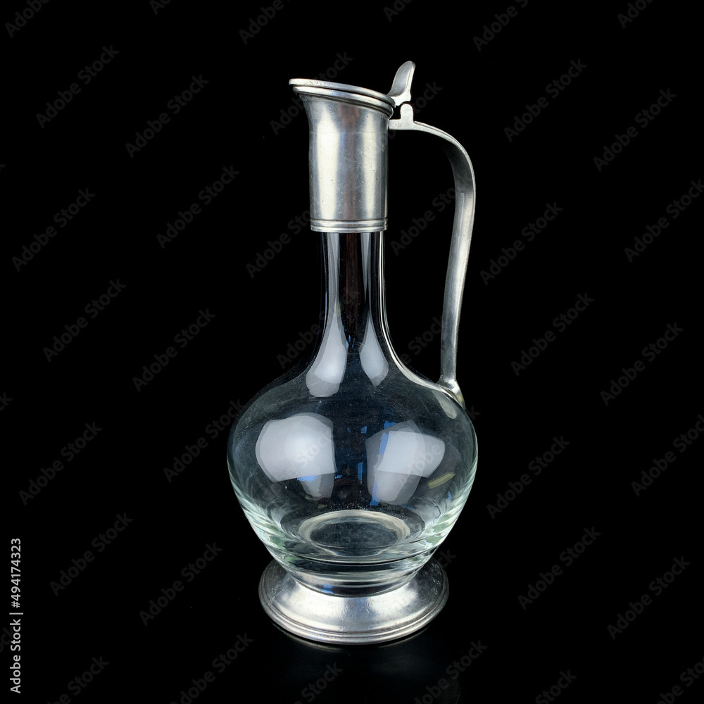 antique glass decanter with a metal figured neck. retro decanter for alcohol on a black isolated background antique glass decanter with a metal figured neck. retro decanter for alcohol on a black isolated background