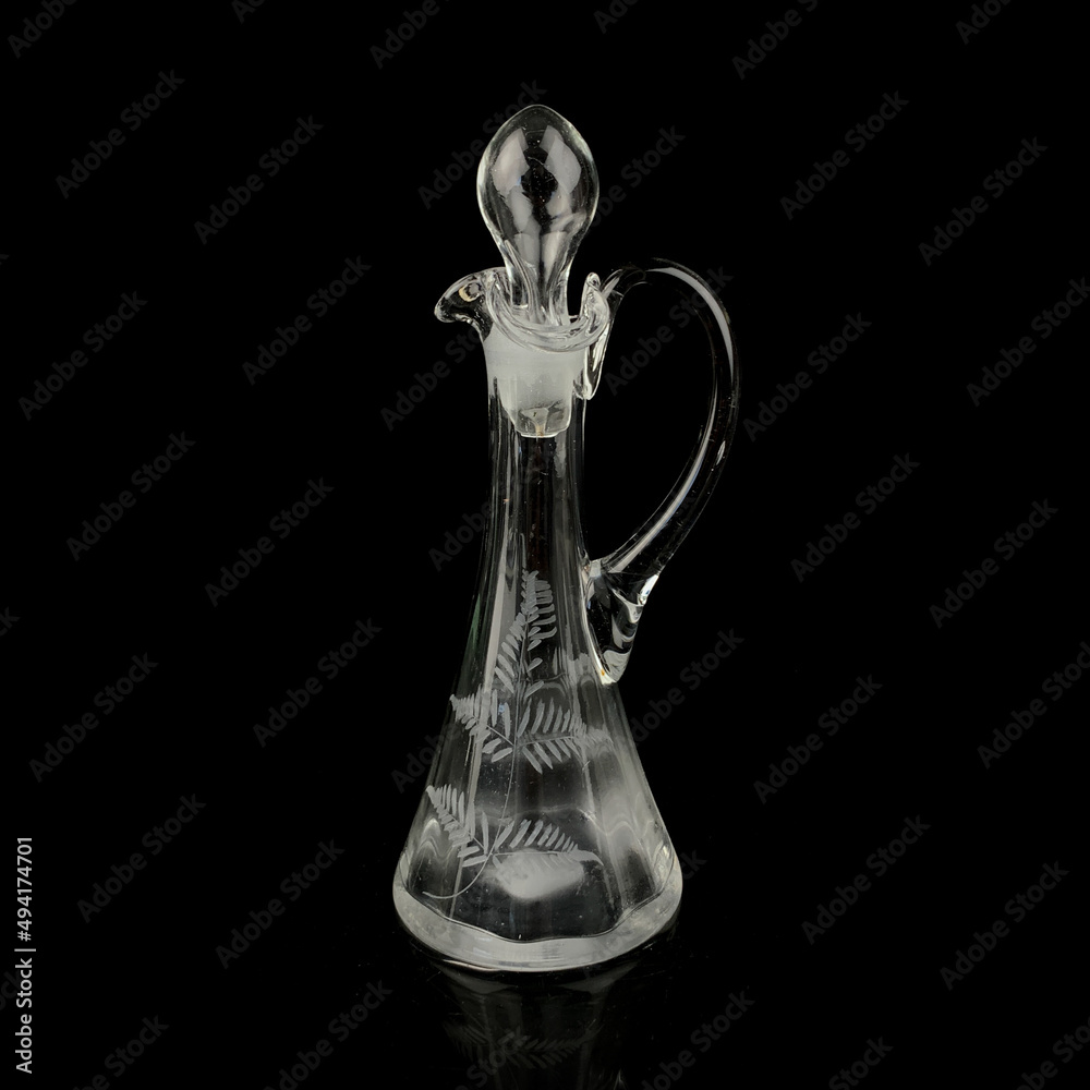 antique glass decanter with geometric pattern. retro decanter for alcohol on a black isolated background. engraved vintage decanter