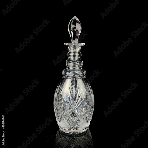 antique glass decanter with geometric pattern. retro decanter for alcohol on a black isolated background. engraved vintage decanter