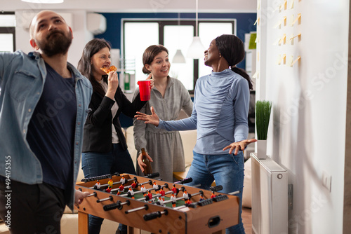 Canvas Print Cheerful people having fun with foosball table game at after work drinks, doing office party celebration with coworkers