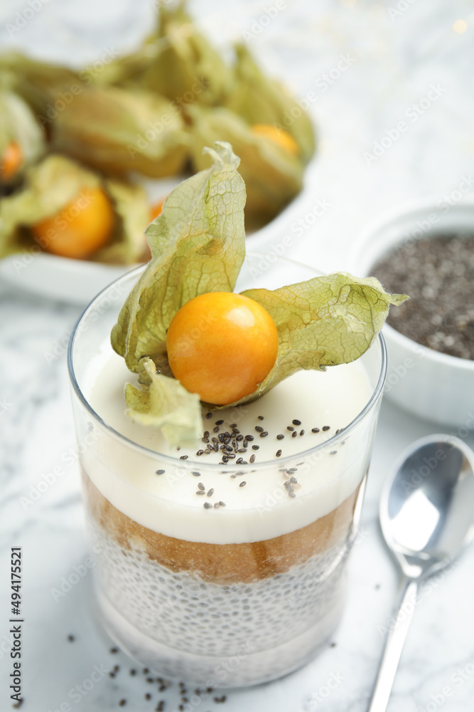 Delicious chia pudding decorated with physalis fruit on white marble table, closeup Delicious chia pudding decorated with physalis fruit on white marble table, closeup