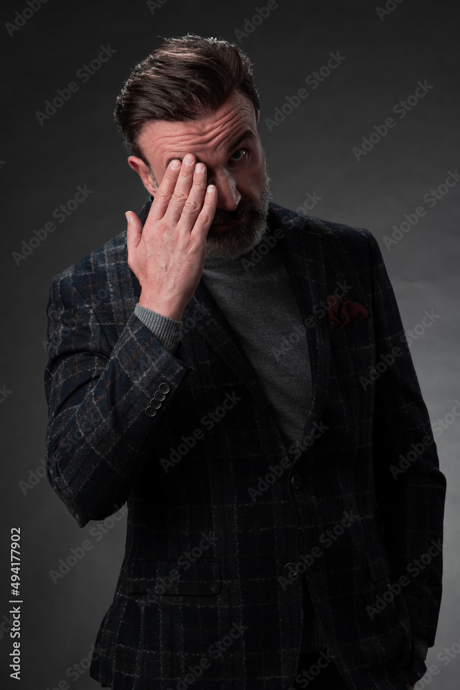 Portrait of a stylish elegant senior businessman with a beard and casual business clothes in photo studio isolated on dark background gesturing with hands Portrait of a stylish elegant senior businessman with a beard and casual business clothes in photo studio isolated on dark background gesturing with hands