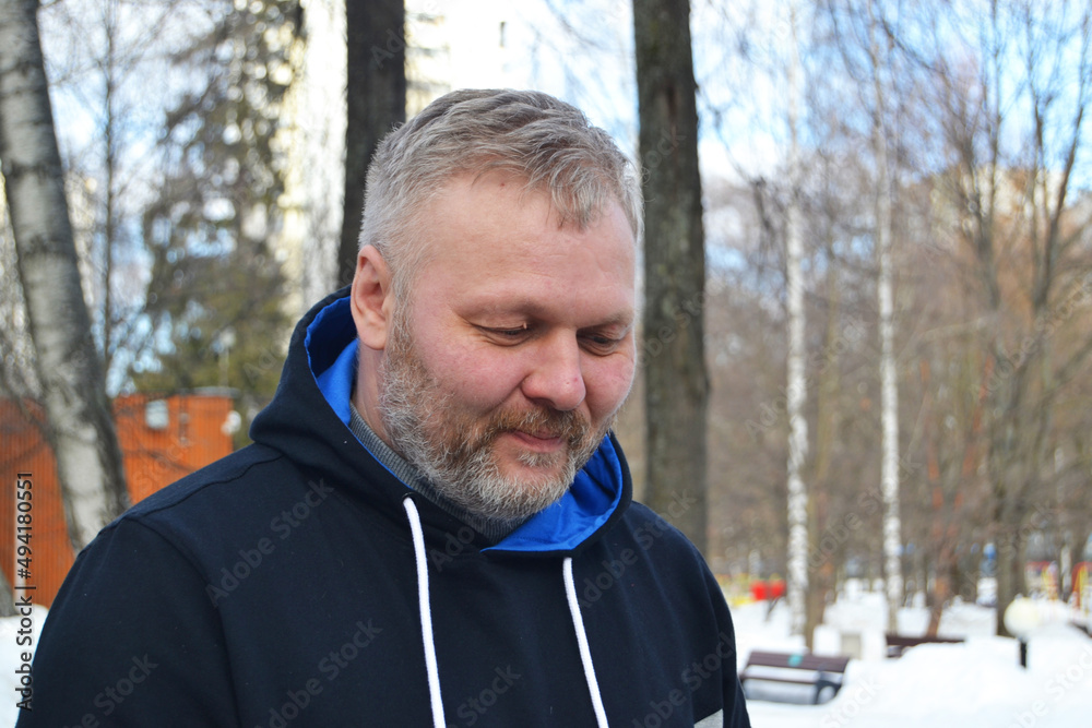 A gray-haired man with a beard on the street is smiling A gray-haired man with a beard on the street is smiling