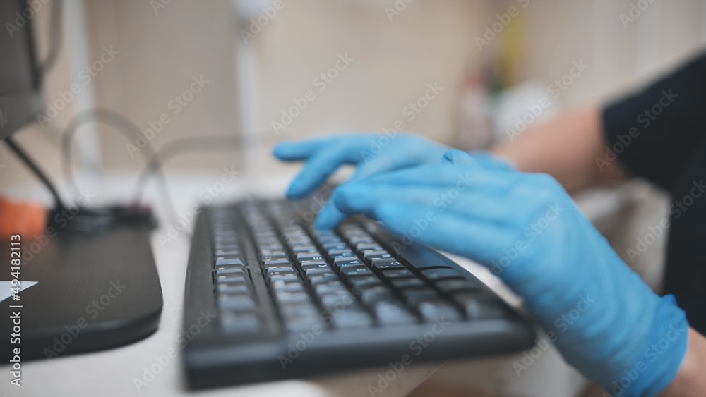 The veterinarian is typing on the keyboard in blue gloves. The veterinarian is typing on the keyboard in blue gloves.
