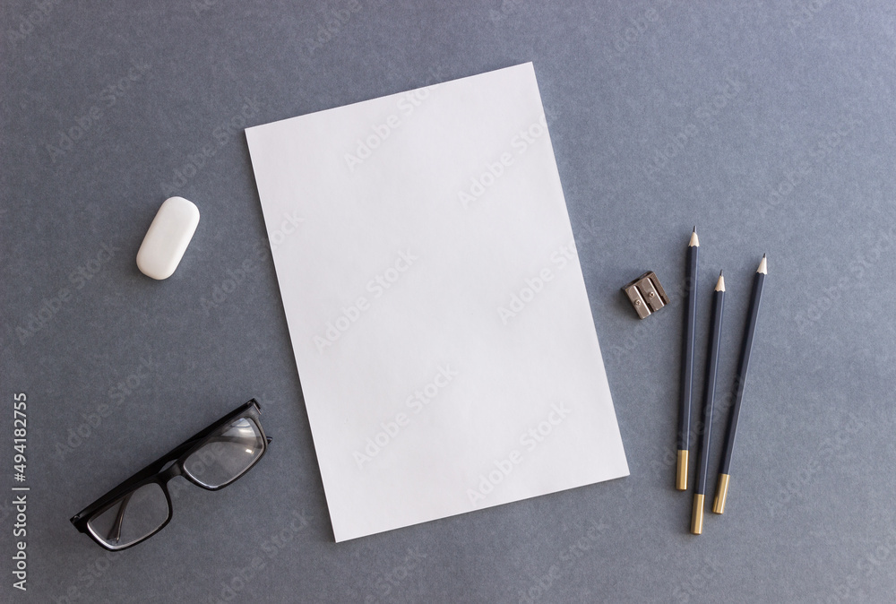 White paper and pencils on a gray background. Design. Mock up. Copy space. White paper and pencils on a gray background. Design. Mock up. Copy space.