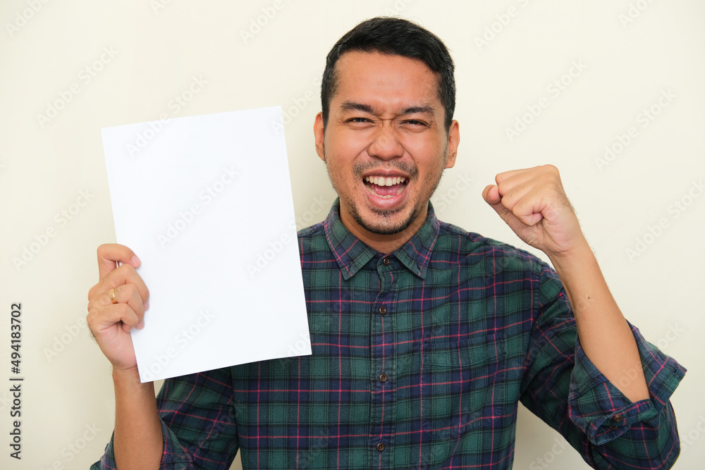 Closeup portrait of adult Asian man showing blank white paper with happy expression Closeup portrait of adult Asian man showing blank white paper with happy expression
