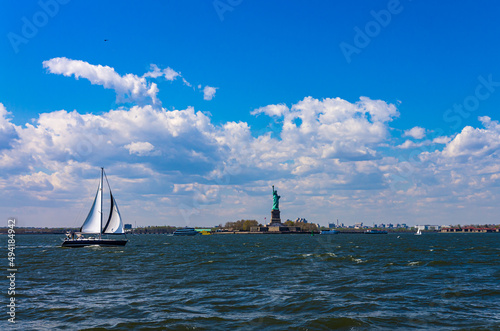Statue of liberty from water on sunny day , with sail ship