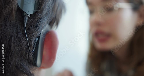 a woman speech therapist, deals with a person with hearing problems, articulates words. close-up hearing aid photo