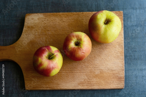 Three apples on a cutting board