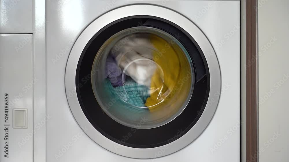 Colorful laundry inside a front loader washing machine spinning clockwise