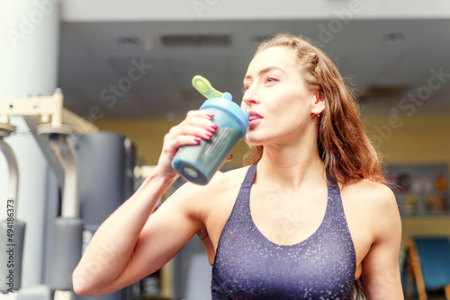 Preparing and consuming a protein supplement. Building muscle mass. Sports girl in the gym. Active lifestyle of a woman