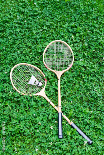 Badminton rackets with a shuttlecock on green grass.