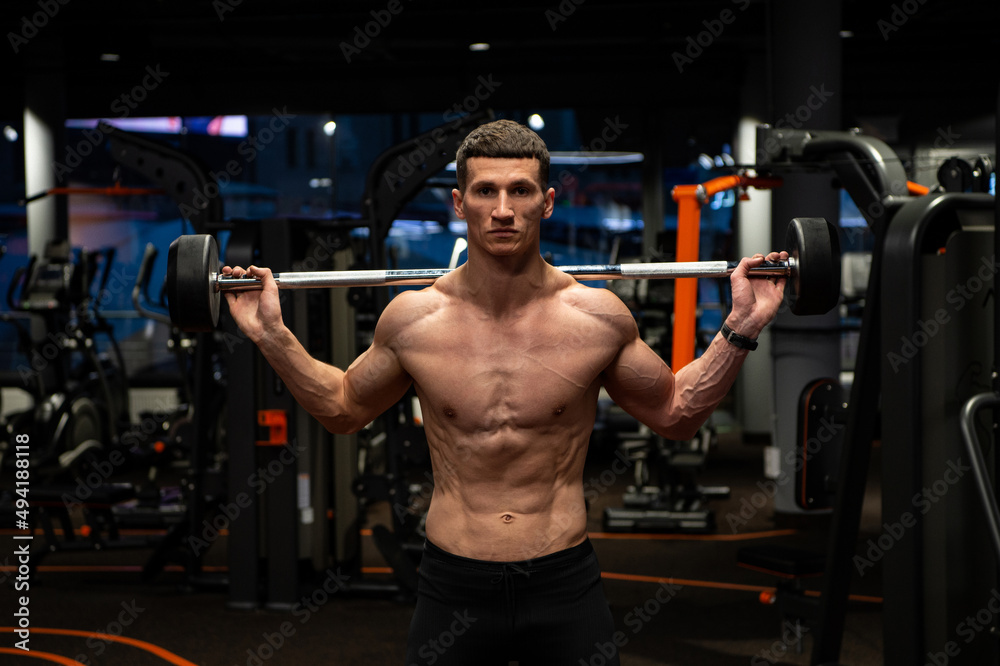 Naklejka premium Shirtless weightlifter man lifting barbell in gym, weightlifting