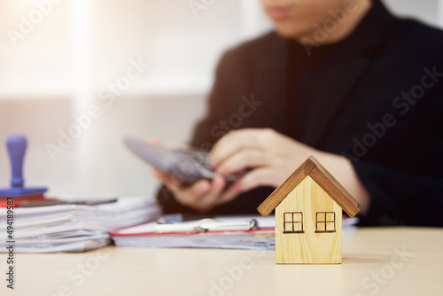 Business concept of house trading Certification. present price contract on trading rent a house to customers. Insurance Agent house. wooden house on table in real estate sales office.