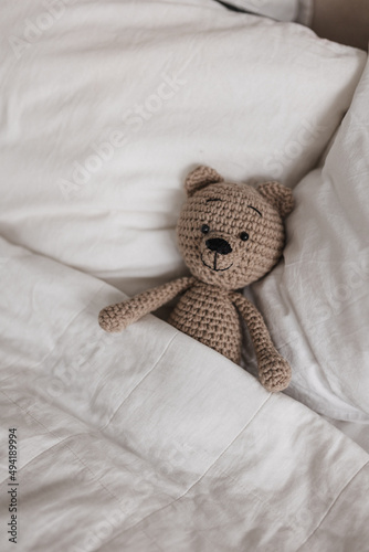 Knitted teddy bear in the bright interior of the room