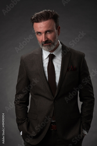 Portrait of a stylish elegant senior businessman with a beard and casual business clothes in photo studio isolated on dark background gesturing with hands © .shock