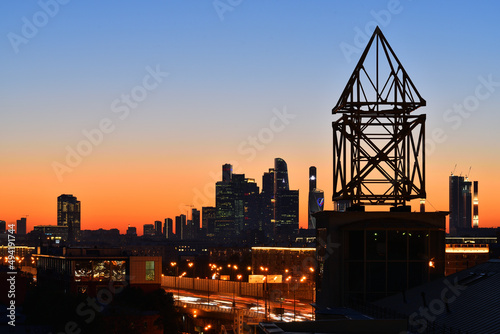 Moscow city at night. Silhouette of radio antenna in the foreground.